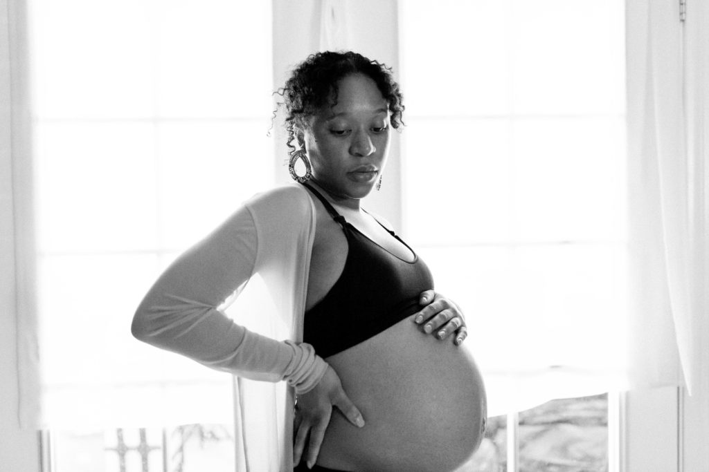 Pregnant African American woman holding her belly and looking down