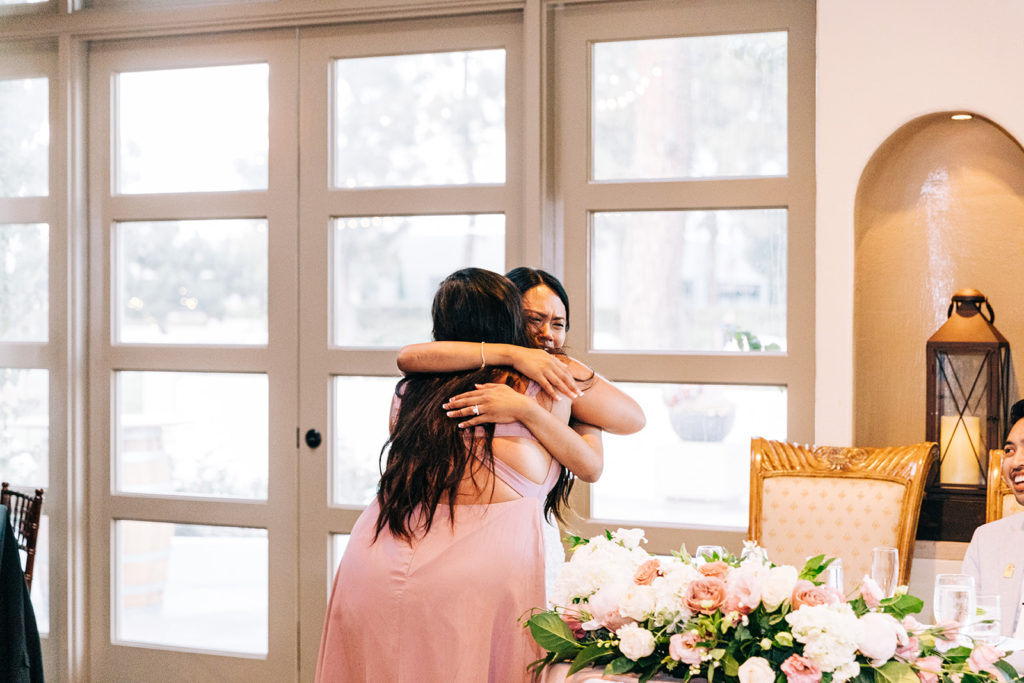 A photo of two women hugging and crying at a wedding.