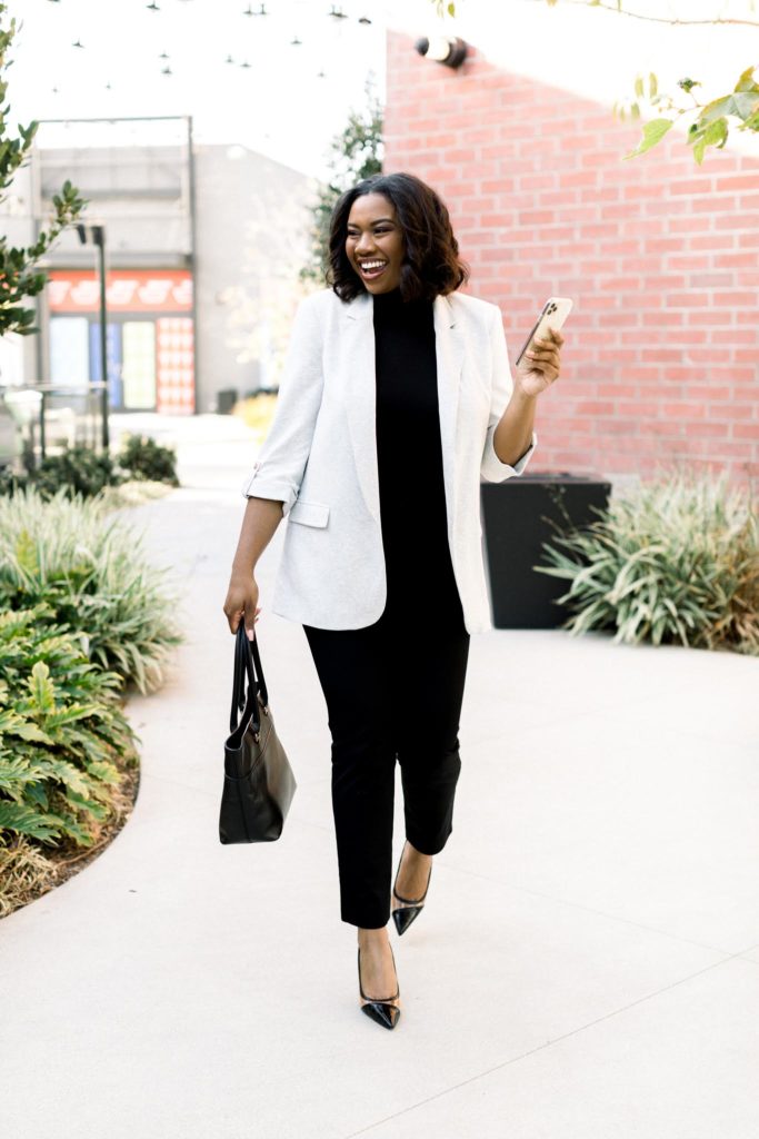 Black female blogger smiling and walking with phone in hand