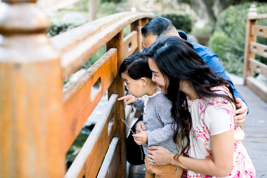 The Gomez family looking over the side of a bridge during their family photography session in Pomona.