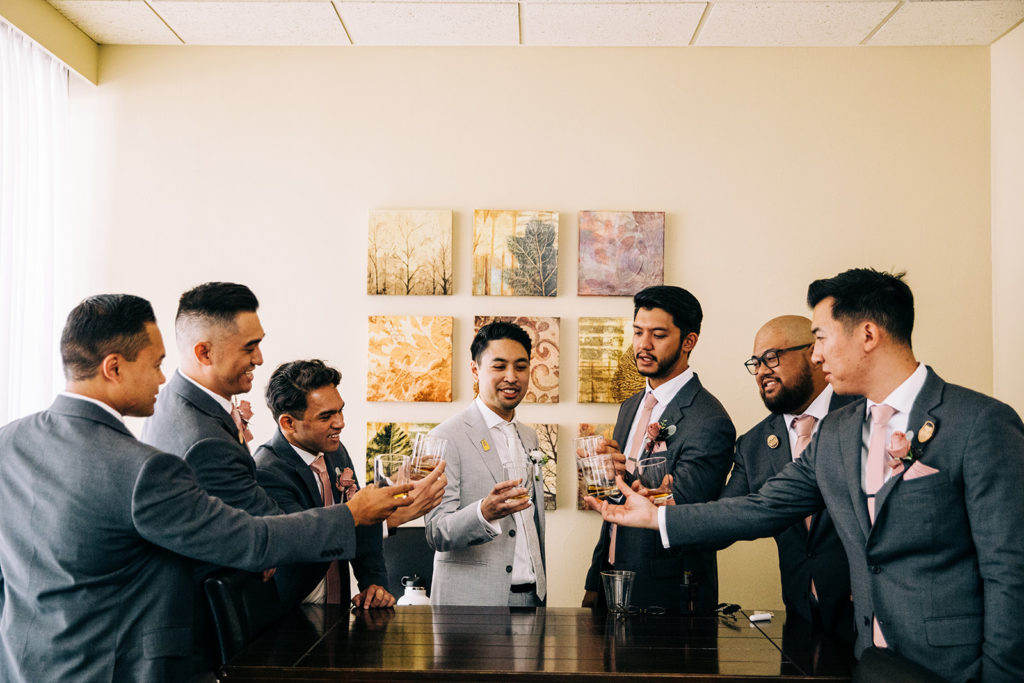 A groom and his groomsmen having a final toast before joining the wedding reception.