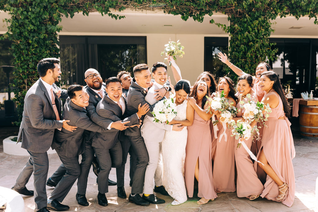 An entire wedding party hugging and cheering on the bride and groom.